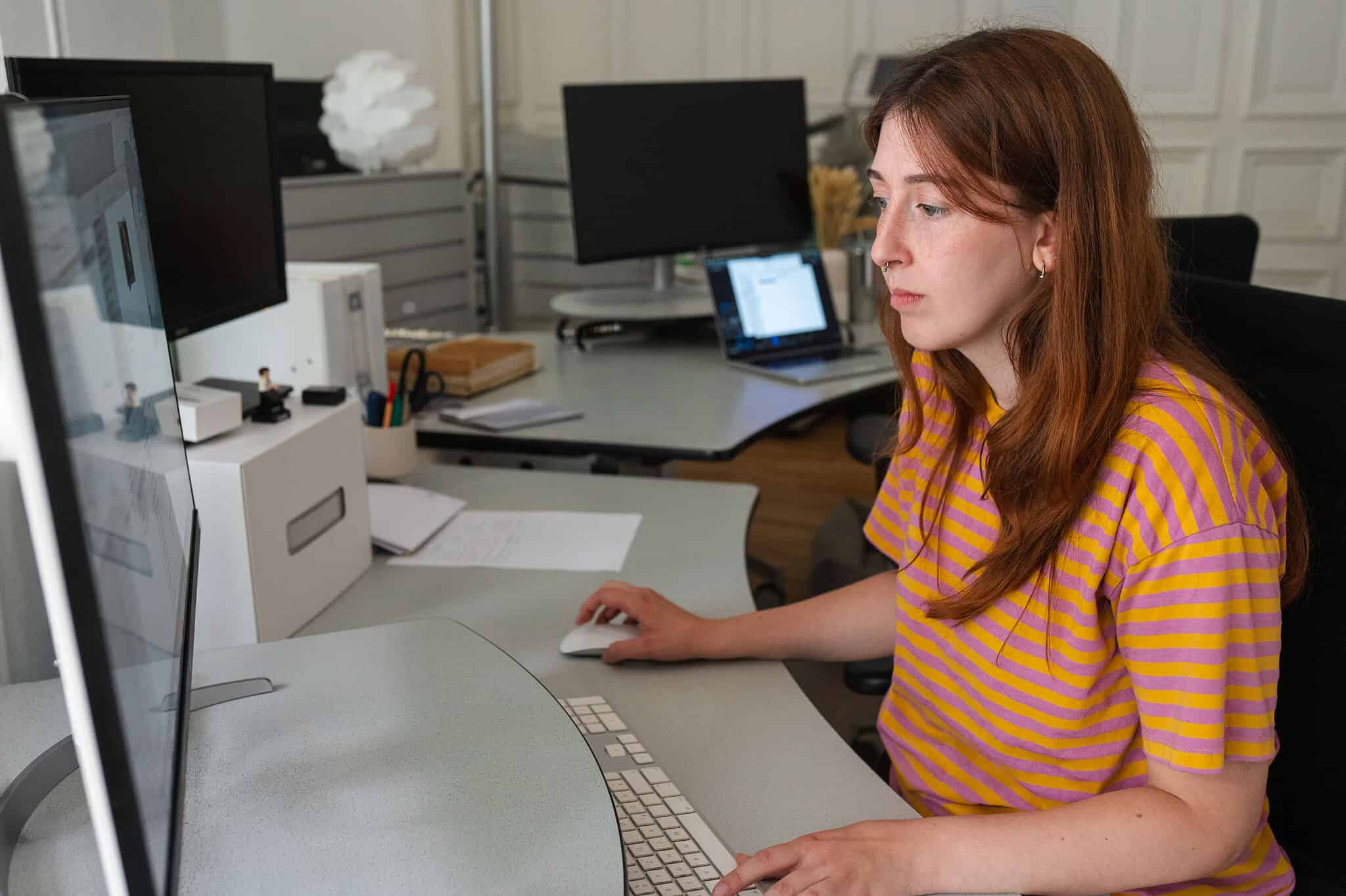 Mitarbeiterin bei der konzentrierten Arbeit am Computer in einem modernen Büro.