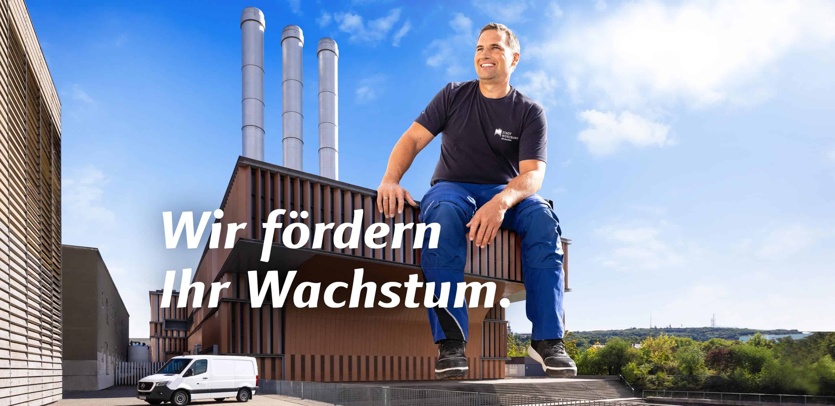 Mitarbeiter der Stadt Würzburg vor einem Betriebsgebäude mit dem Motiv „Wir fördern Ihr Wachstum“.